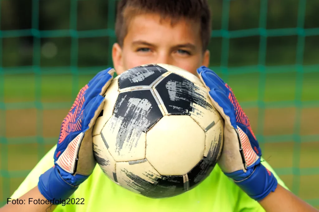 Junge trägt Torwandhandschuhe für Kinder und Jugendliche und hält einen Fußball in der Hand - 5YKH3J4 - Foto Fotoerfolg2022